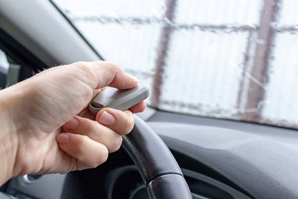 Woman hand inside the car, driver using remote control to open the automatic gate while leaving home